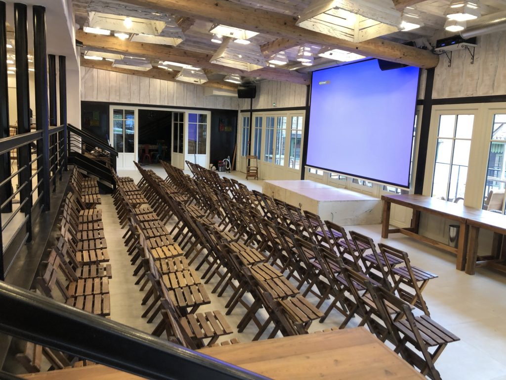 Photo d'une grande salle avec des chaises devant un écran de projection